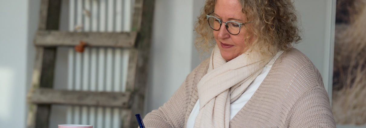 Andrea Fischer macht sich am Schreibtisch Notizen bei einer Tasse Tee